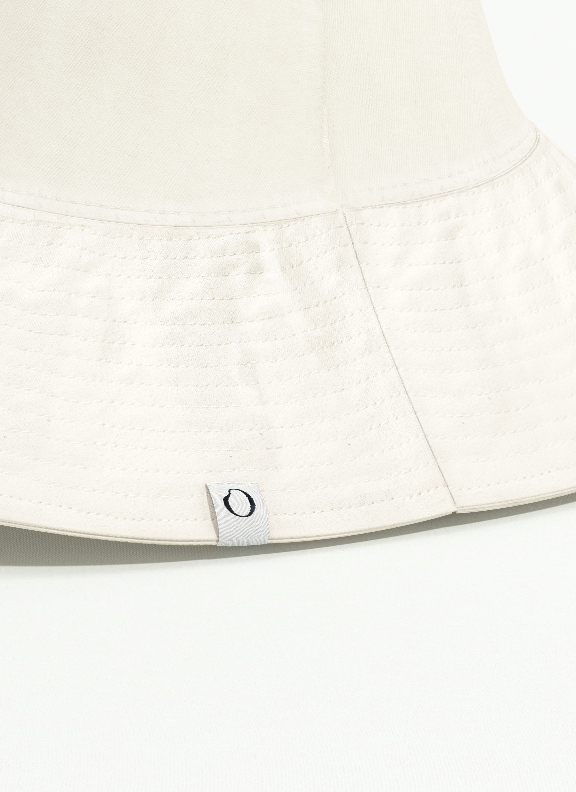 Close-up of a wide brim hat in beige, with a visible ondine tag showing the letter 'O'.